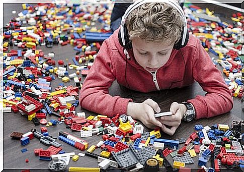 Boy playing on cell phone with legos around