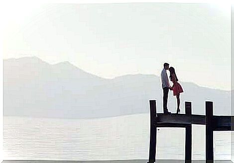 couple kissing on a deck