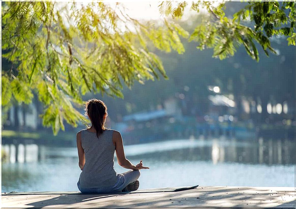 woman meditating in front of lake